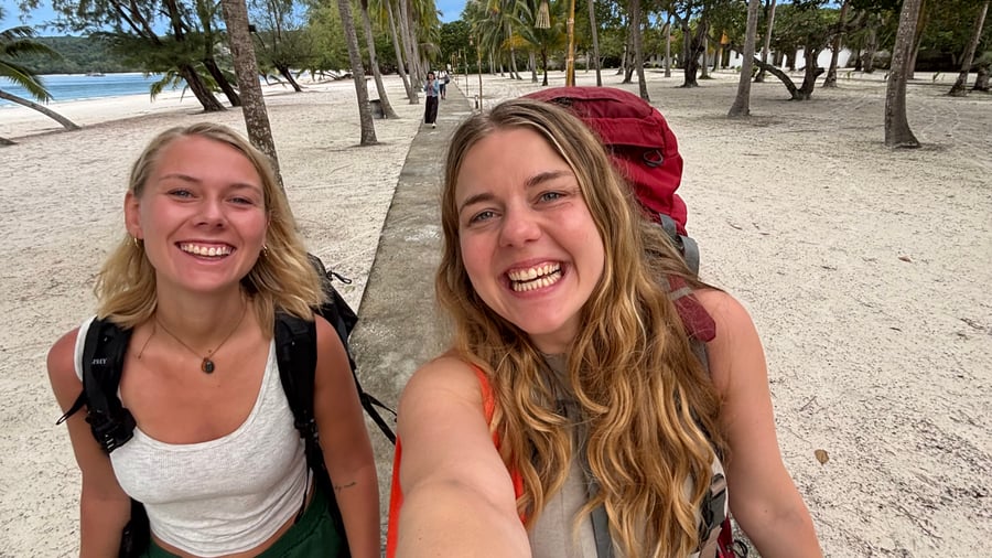 Two girls backpacking across beach in Cambodia