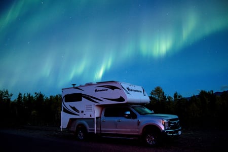 Truckcamper under nordlys i Yukon
