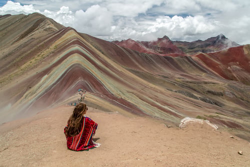 Girl looking out over rainbow mountain