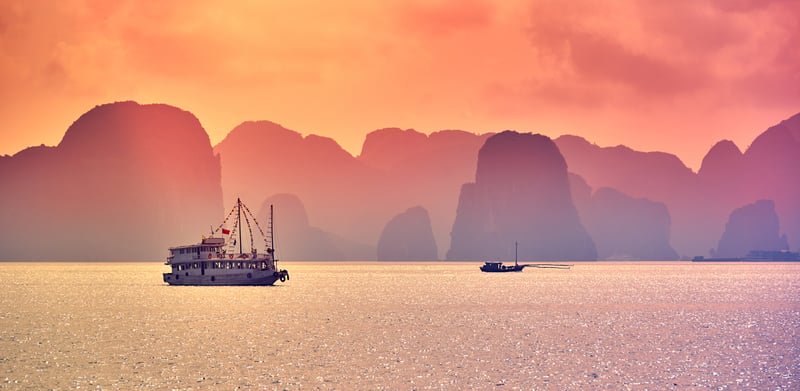 Halong Bay med skepp i solnedgången