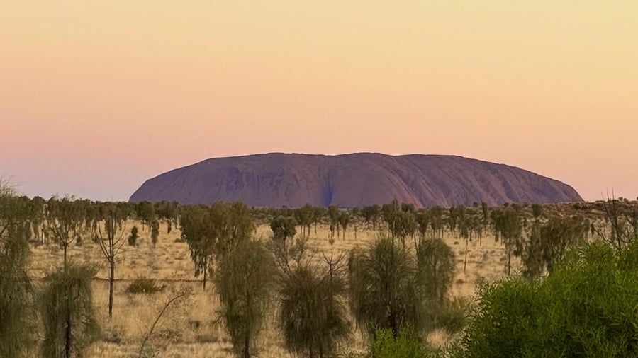 Uluru skiftar i färg under dagen