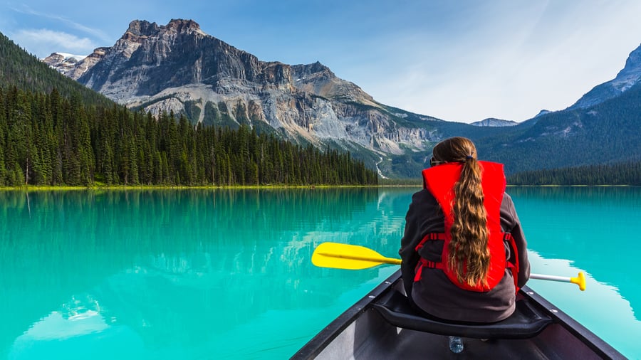 Paddling across turquoise lake under rocky peaks