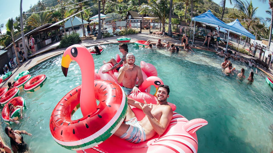 Guys chilling in a pink flamingo in the pool