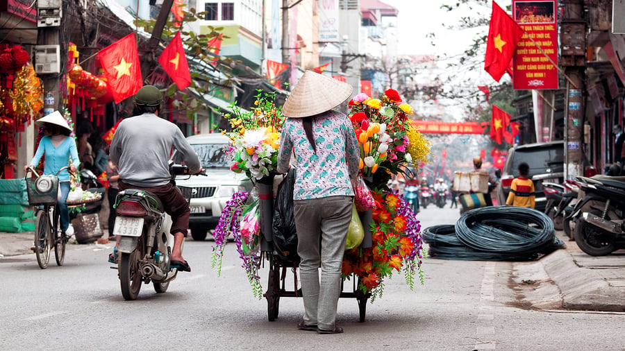 Woman with a cart full of flowers on a busy street