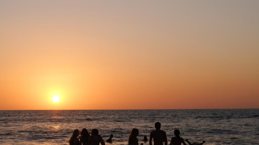 Groep mensen die zwemmen tijdens zonsondergang