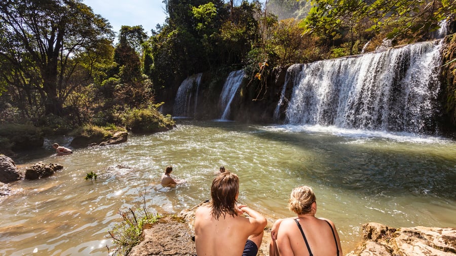 Friends exploring and swimming in waterfall