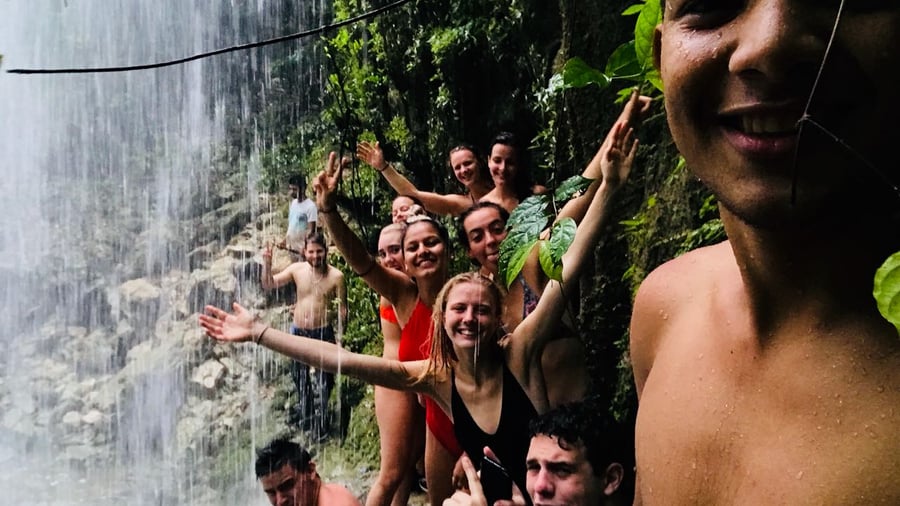 Groep mensen zwemt bij een waterval in het bos