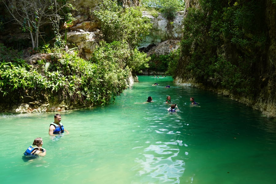 People swimming in a clear blue cenote